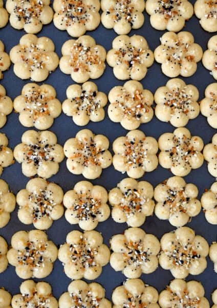 Golden Southern cheese crackers (savory spritz cookies) pressed into flower shapes and sprinkled with everything seasoning.