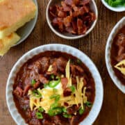 Chipotle Chili con Carne in large bowl topped with sour cream, cheddar cheese and sliced scallions