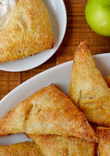 Easy Apple Turnovers on serving plate next to a small bowl with whipped cream