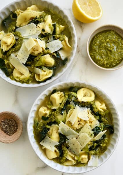 Two bowls containing Quick Tortellini Soup with Greens topped with pesto
